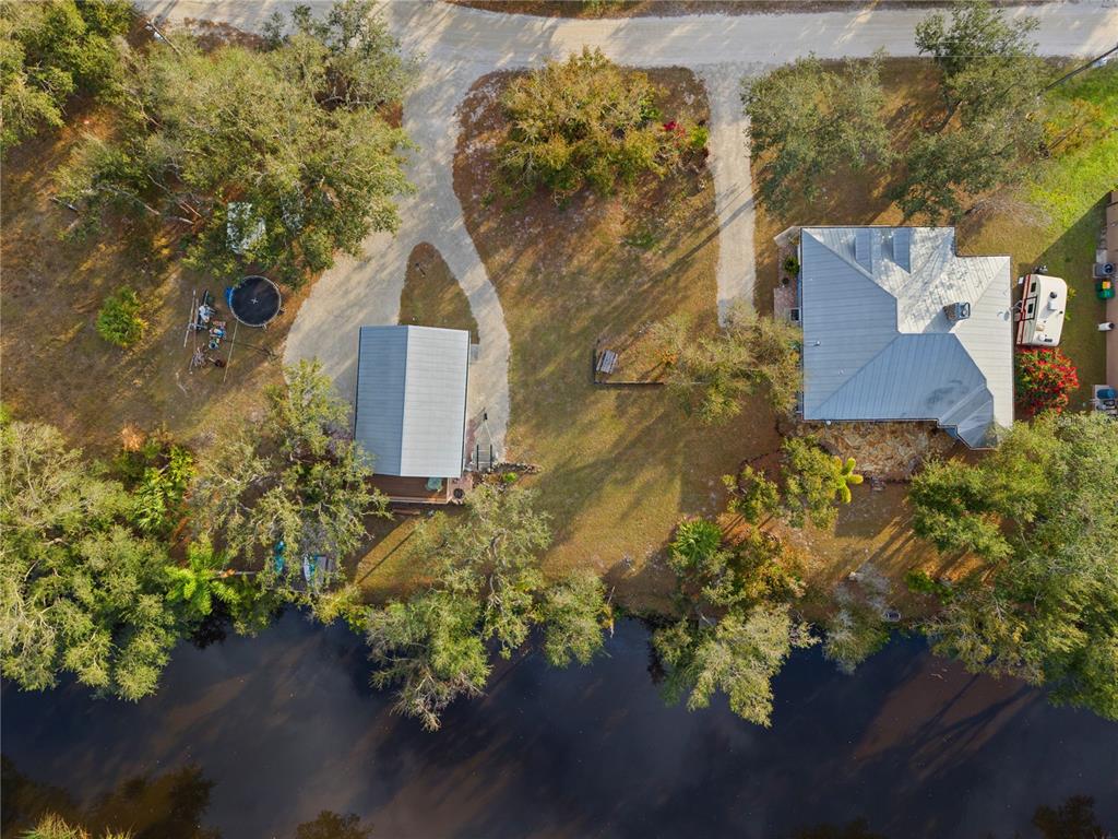 An aerial view shows a house and a detached building on a grassy waterfront lot — 27350 SAN CARLOS DRIVE, PUNTA GORDA, FL