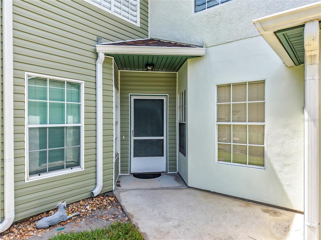 The exterior entrance features a concrete porch, a screen door, and light green siding — 3022 COTTAGE GROVE COURT UNIT 1807, ORLANDO, FL