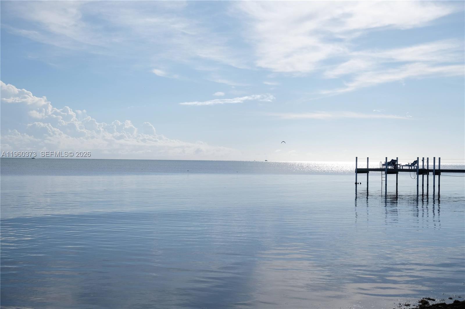 A wooden pier extends into a calm, expansive body of water under a cloudy sky — 1557 Long Beach Dr, FL 33043, FL