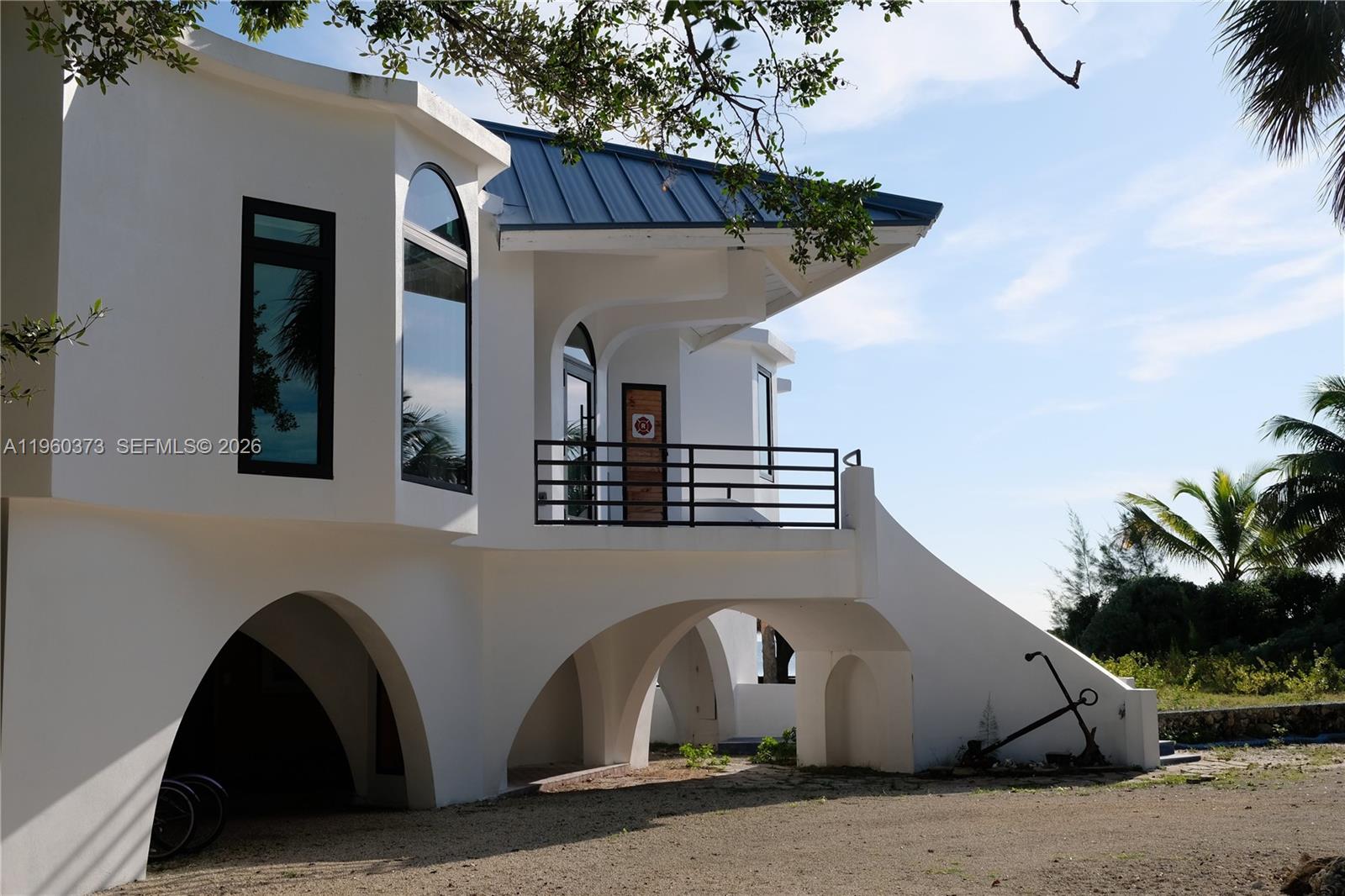 A white multi-story house with arched lower-level openings and a metal roof — 1557 Long Beach Dr, FL 33043, FL