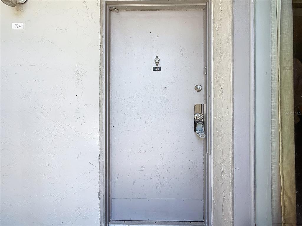 A light-colored exterior door with a lockbox and unit number 724 — 2625 STATE ROAD 590 UNIT 724, CLEARWATER, FL