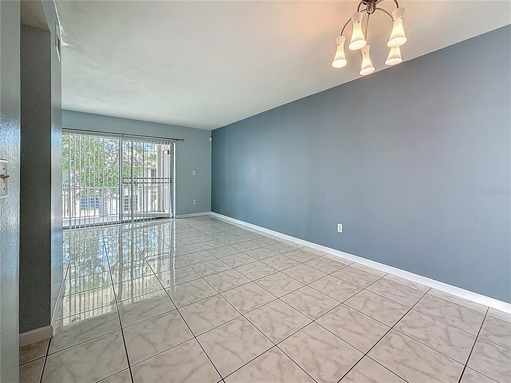 An empty room features light-colored tile flooring, a blue accent wall, and a sliding glass door — 2625 STATE ROAD 590 UNIT 724, CLEARWATER, FL
