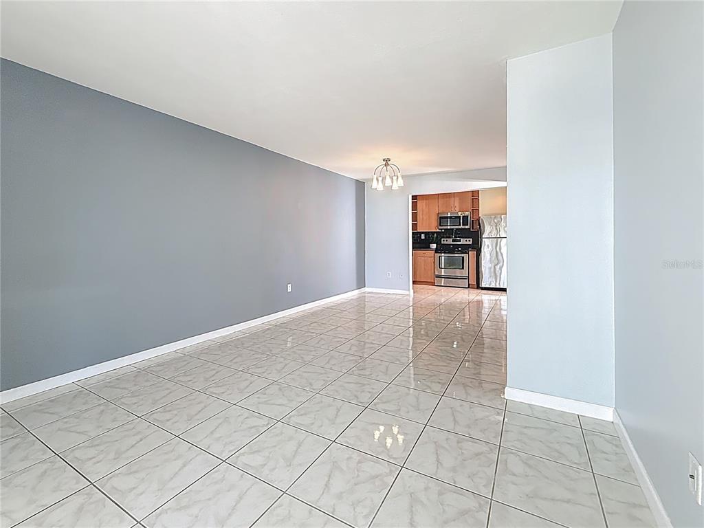 An open-concept living and dining area features gray walls, light tile flooring, and a kitchen — 2625 STATE ROAD 590 UNIT 724, CLEARWATER, FL