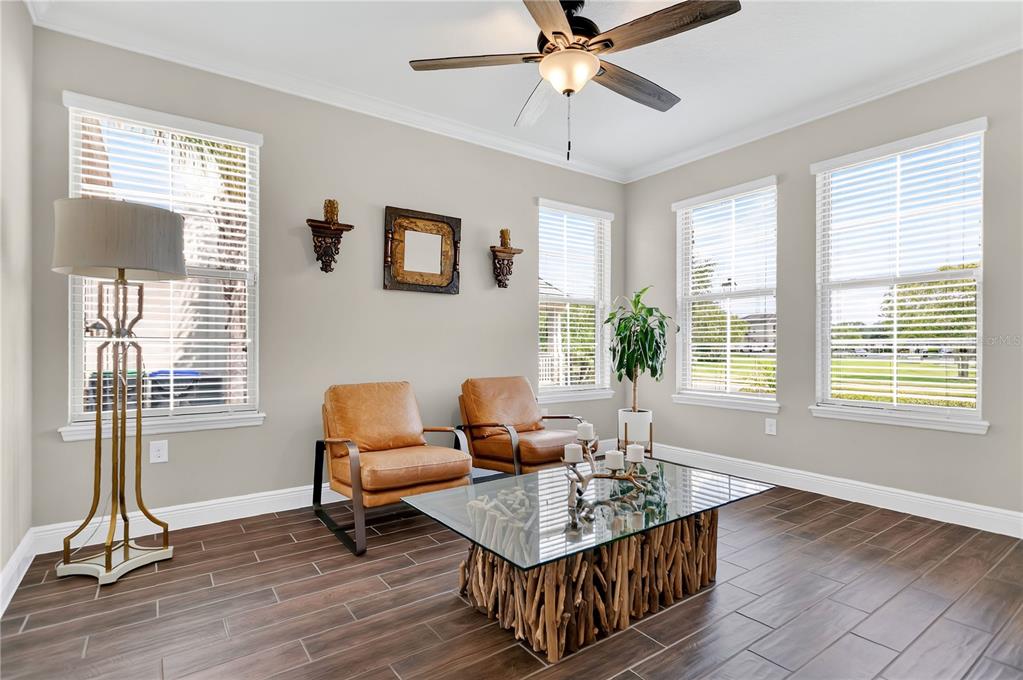 A living room features two leather chairs, a glass-topped driftwood coffee table, and tile flooring — 10007 LITTLE ALCOVE LOOP, WINTER GARDEN, FL