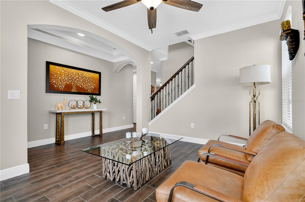 A living room features two leather chairs, a driftwood coffee table, and a staircase — 10007 LITTLE ALCOVE LOOP, WINTER GARDEN, FL