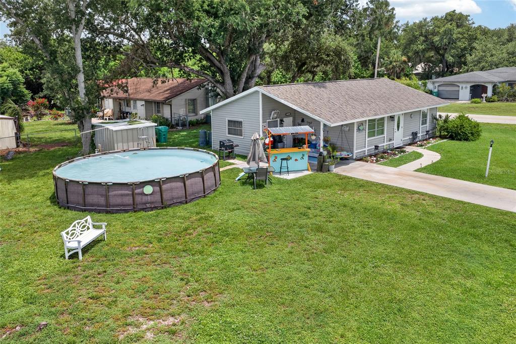 An aerial view of a gray house with a backyard pool, tiki bar, and lawn — 1608 YANCY STREET, PORT CHARLOTTE, FL