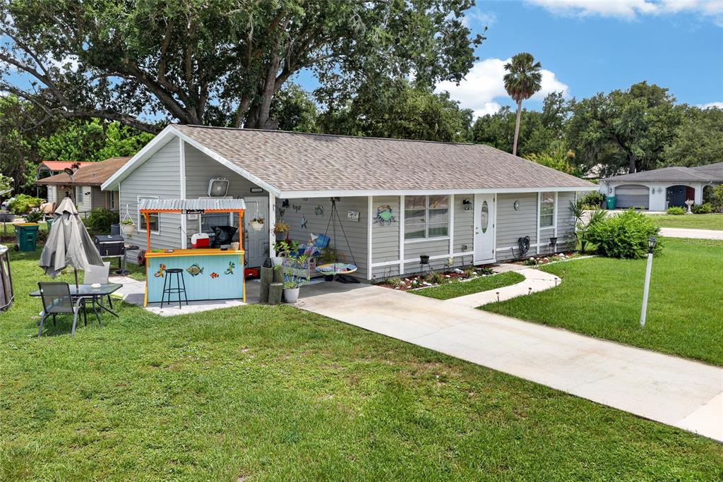 A light gray single-story house features a front carport, a tiki bar, and a driveway — 1608 YANCY STREET, PORT CHARLOTTE, FL