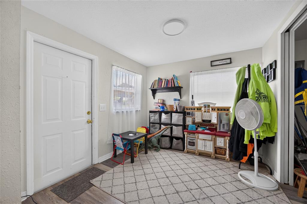 A playroom with a white door, a rug, a toy kitchen, and a small table — 1608 YANCY STREET, PORT CHARLOTTE, FL