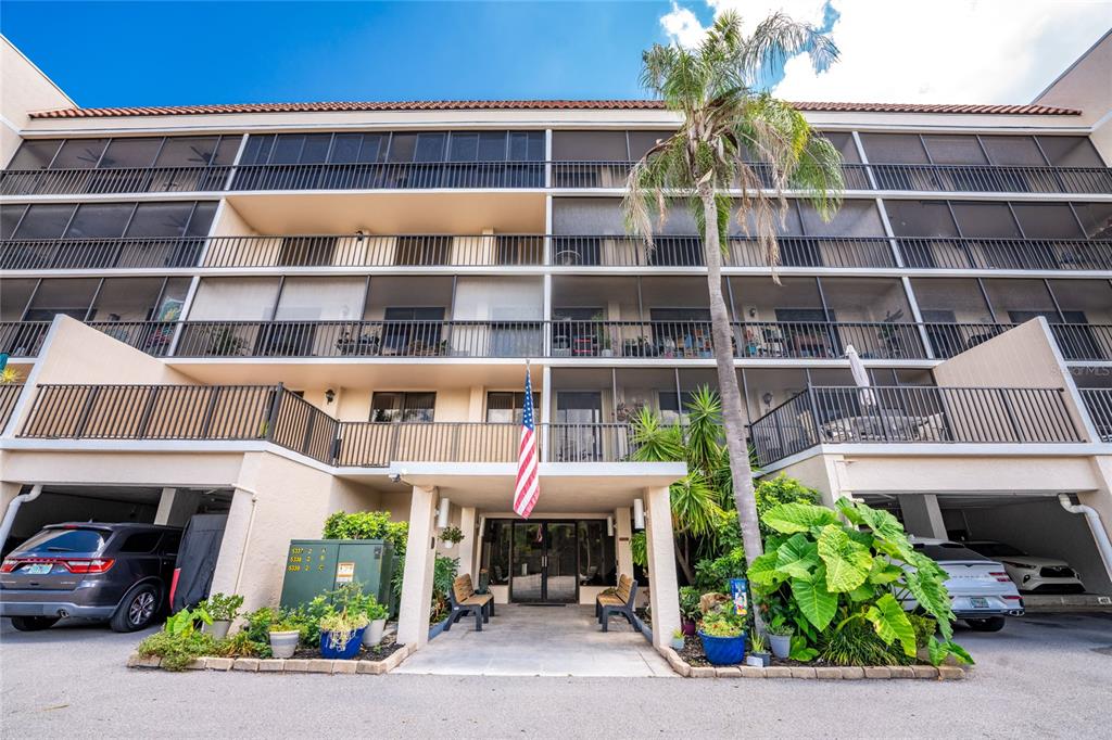 A multi-story apartment building with screened balconies, a covered entrance, and a palm tree — 25188 MARION AVENUE UNIT D101, PUNTA GORDA, FL