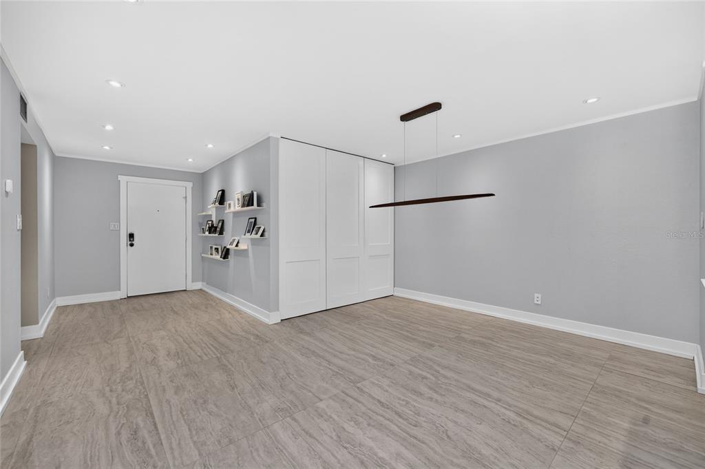 A room with light gray walls, wood-look tile flooring, white paneled doors, and floating shelves — 25188 MARION AVENUE UNIT D101, PUNTA GORDA, FL