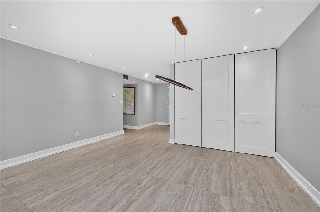 A room with light gray walls, wood-look tile flooring, and a modern pendant light fixture — 25188 MARION AVENUE UNIT D101, PUNTA GORDA, FL