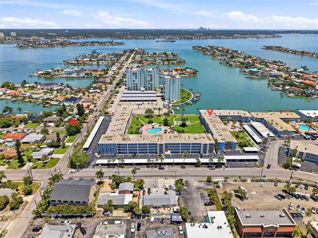 An aerial view shows a multi-story apartment complex with a pool and parking lots — 6201 2ND STREET E UNIT 106, ST PETE BEACH, FL