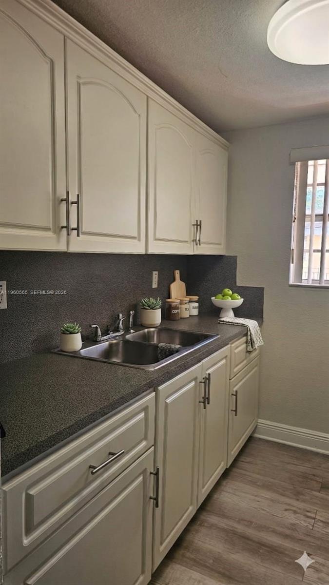 A kitchen features off-white cabinets, a dark speckled countertop, a double sink, and wood-look flooring — 3800 SW 102nd Ave # 221, Miami FL 33165, MIAMI, FL