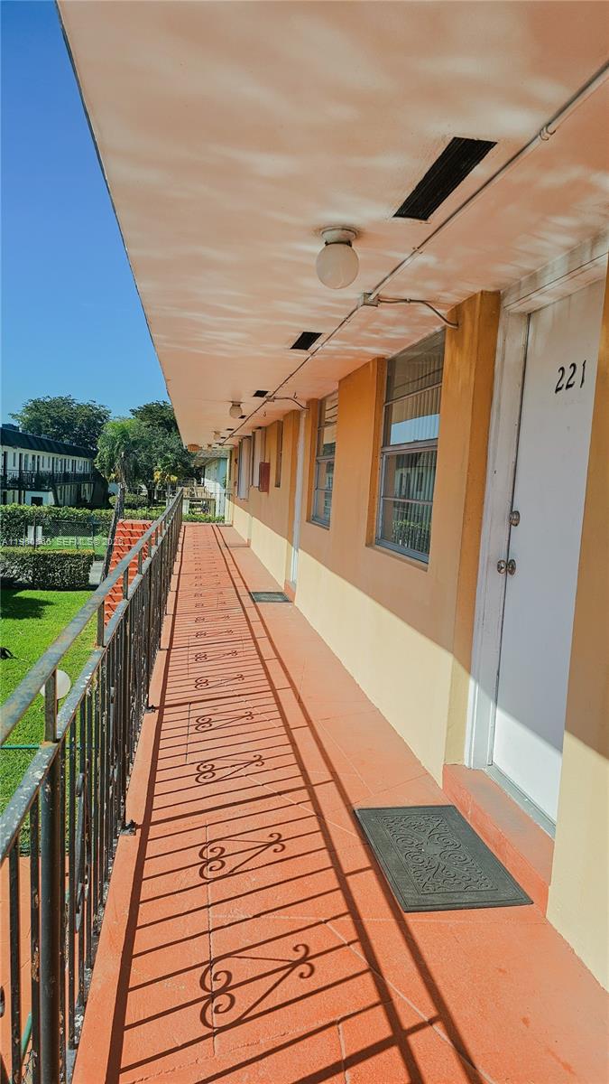 An exterior walkway with orange tile flooring and a metal railing leads to apartment 221 — 3800 SW 102nd Ave # 221, Miami FL 33165, MIAMI, FL