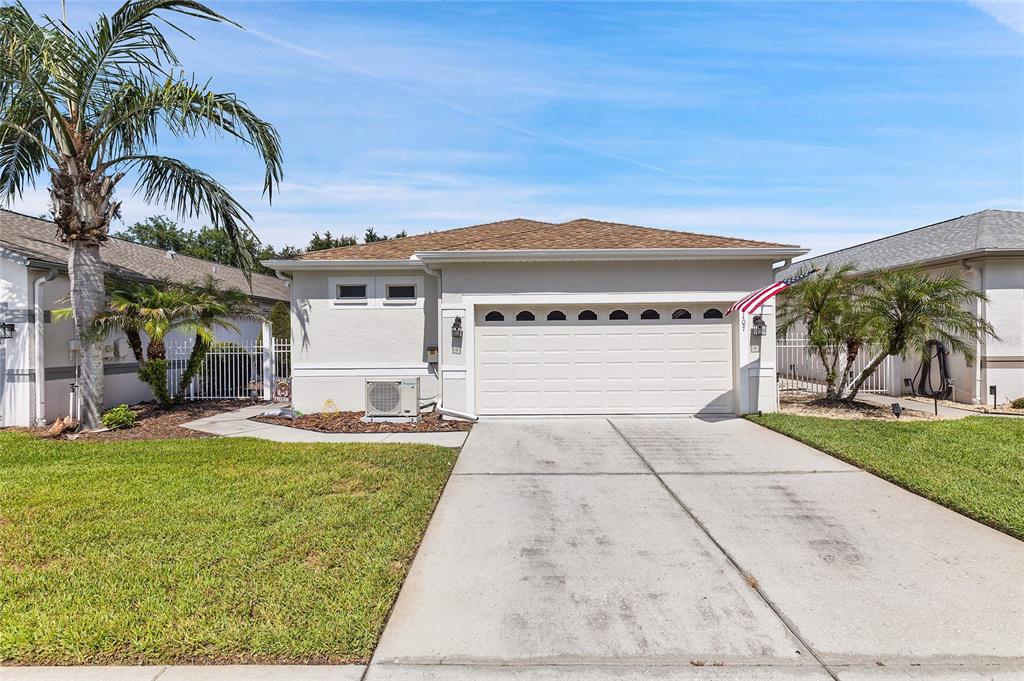 A single-story house with a white stucco exterior, a two-car garage, and a palm tree — 8107 PONKAN ROAD, LAND O LAKES, FL