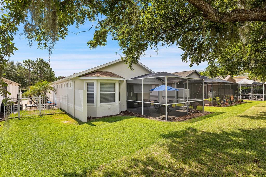 The exterior view shows a house with a screened-in patio and a grassy backyard — 8107 PONKAN ROAD, LAND O LAKES, FL