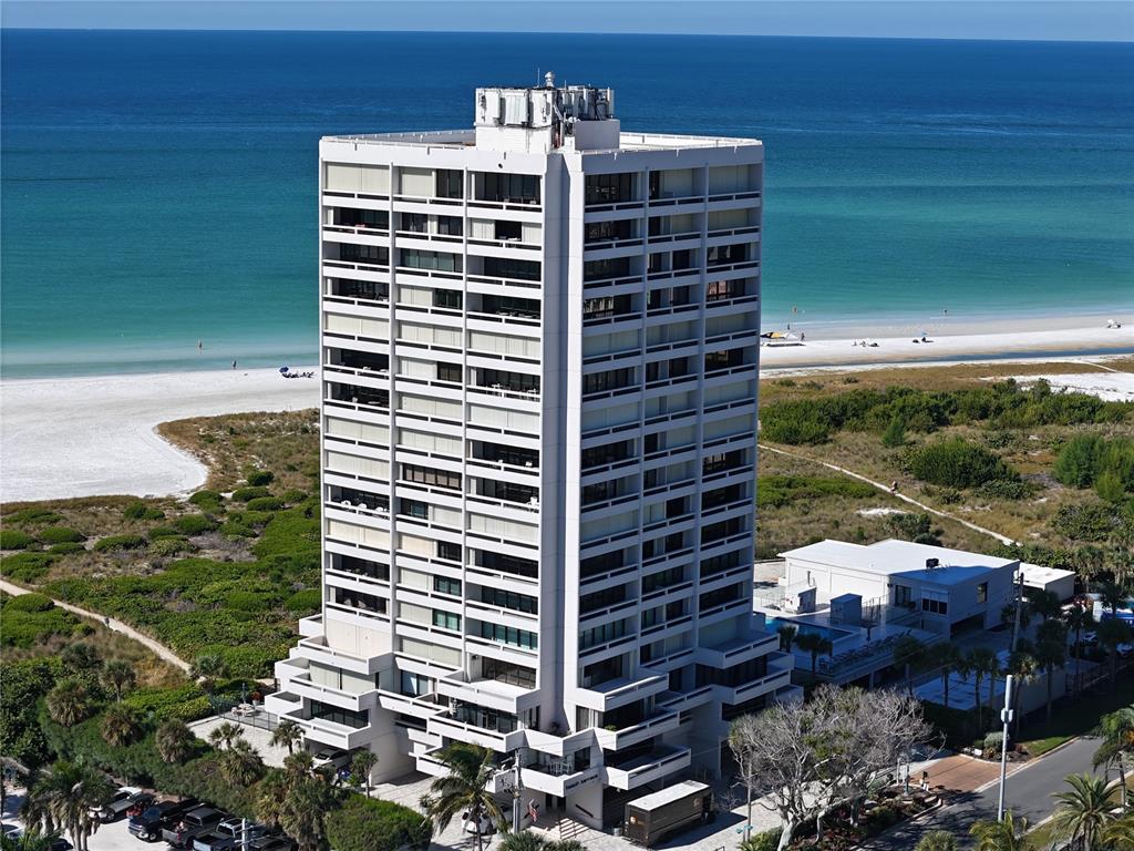 An aerial view of a tall white residential building situated on a sandy beach — 5400 OCEAN BOULEVARD UNIT 10-02, SARASOTA, FL