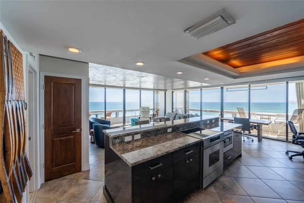 A kitchen with dark cabinets and granite countertops overlooks a living area with ocean views — 5400 OCEAN BOULEVARD UNIT 10-02, SARASOTA, FL
