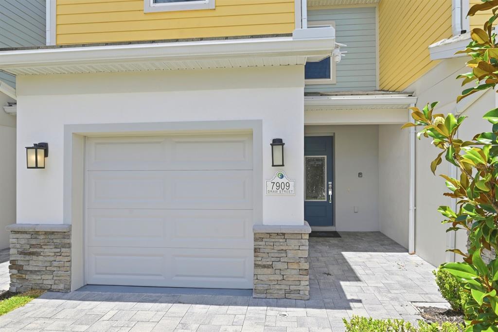 A white garage door and blue front door are visible on this residential building exterior — 7909 DRAW STREET, REUNION, FL