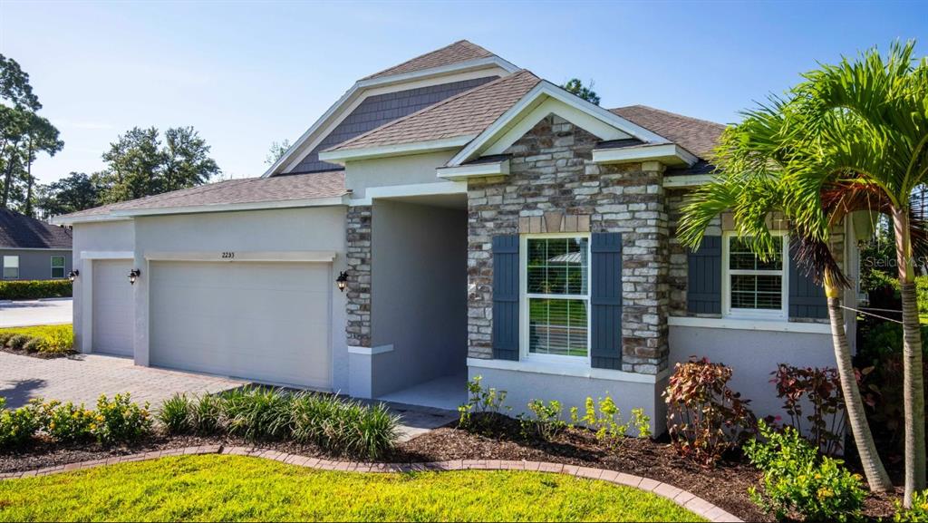 A single-story house exterior features a stone facade, a two-car garage, and a palm tree — 1421 MEREDITH DRIVE, SPRING HILL, FL