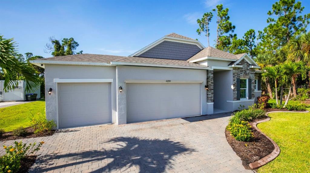 A single-story house with a two-car garage, stone accents, and a paved driveway — 1421 MEREDITH DRIVE, SPRING HILL, FL