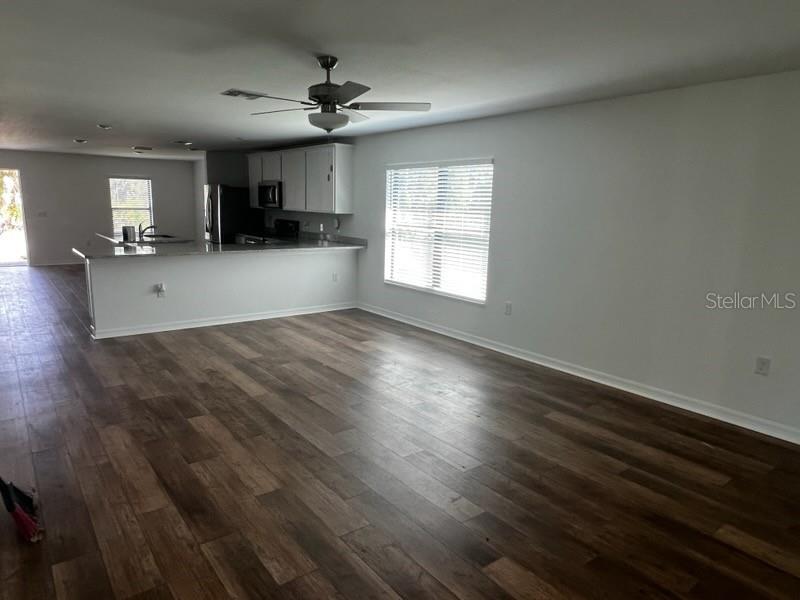 An open-concept kitchen and living area feature wood-look flooring, white cabinets, and a breakfast bar — 1601 LA VETA STREET, NORTH PORT, FL
