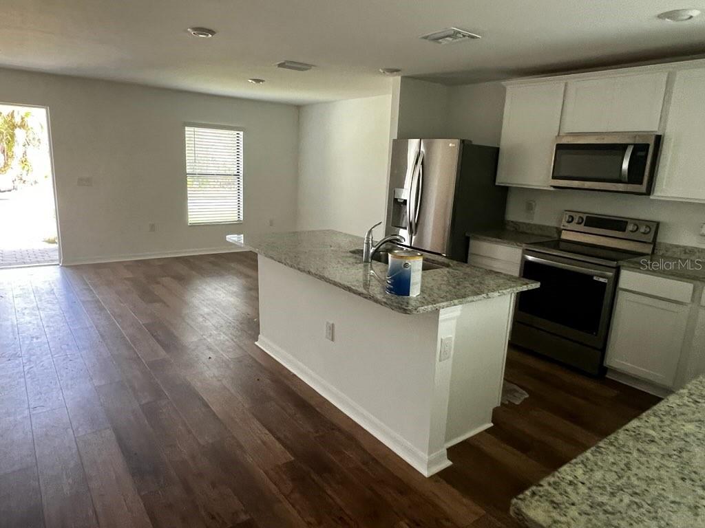 A kitchen with a granite-topped island, stainless steel appliances, and wood-look flooring — 1601 LA VETA STREET, NORTH PORT, FL
