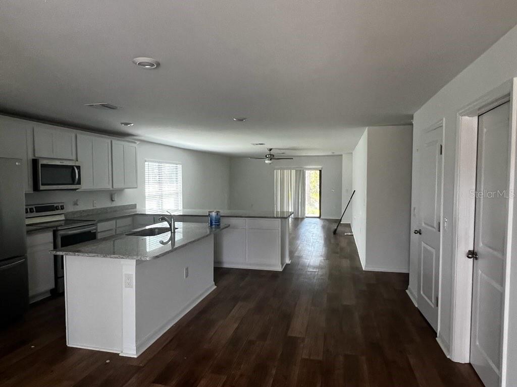 A kitchen with white cabinets and a granite island opens into a living area — 1601 LA VETA STREET, NORTH PORT, FL