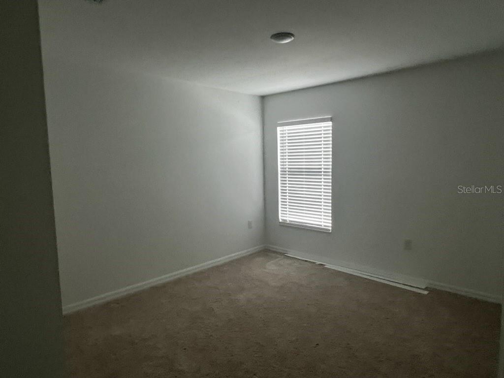 An empty bedroom with beige carpet, light gray walls, and a single window with blinds — 1601 LA VETA STREET, NORTH PORT, FL