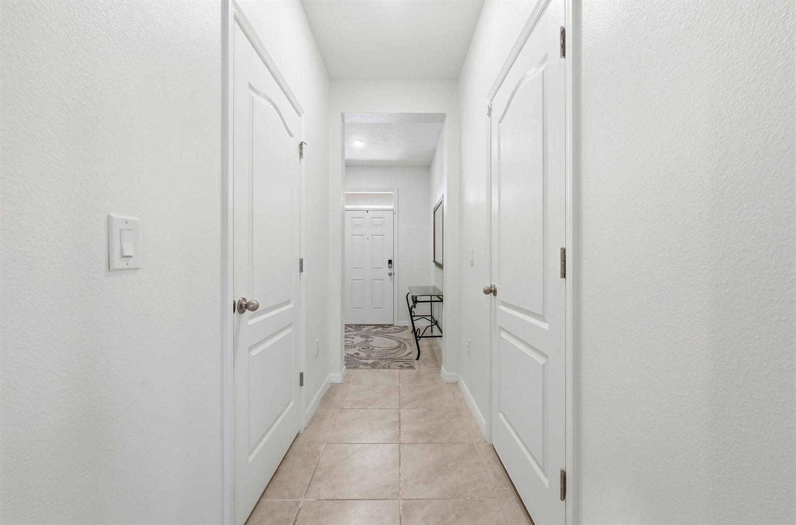 A hallway with tile flooring leads to a white front door with two side doors — 986 Lido Drive, FL 34737, FL