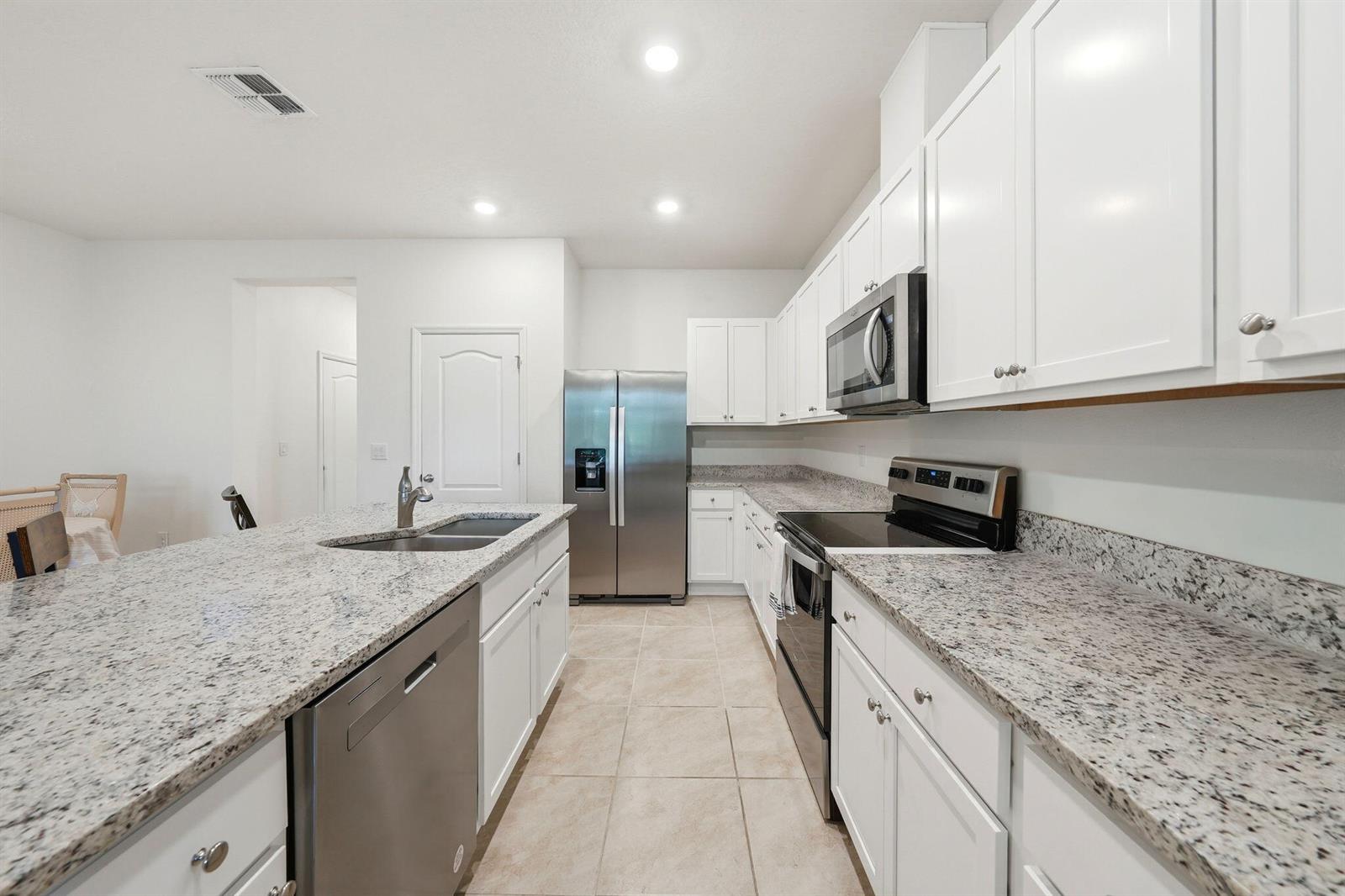 A kitchen features white cabinets, granite countertops, stainless steel appliances, and tile flooring — 986 Lido Drive, FL 34737, FL