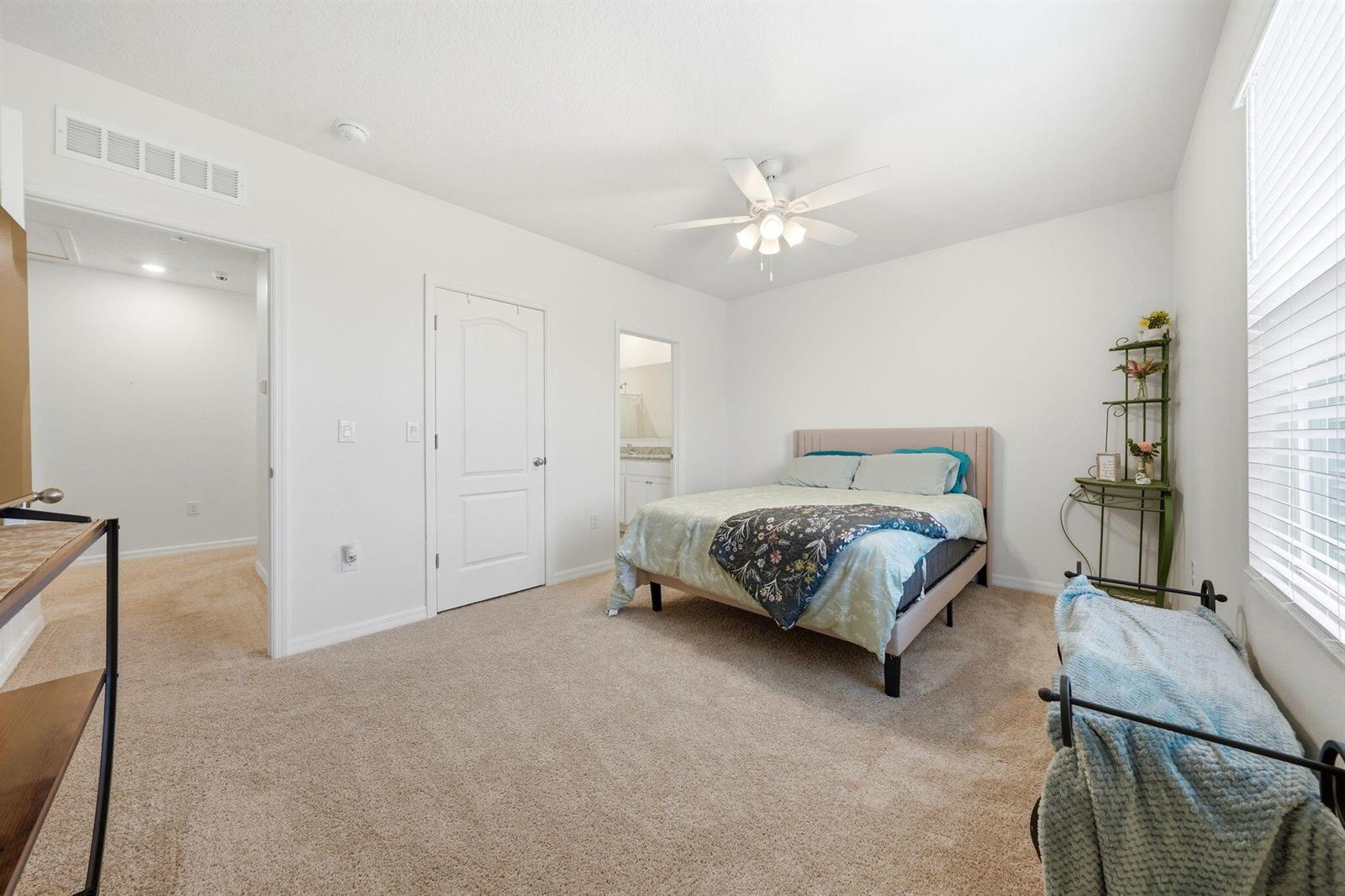 A bedroom with beige carpet, a bed, a ceiling fan, and two doorways — 986 Lido Drive, FL 34737, FL