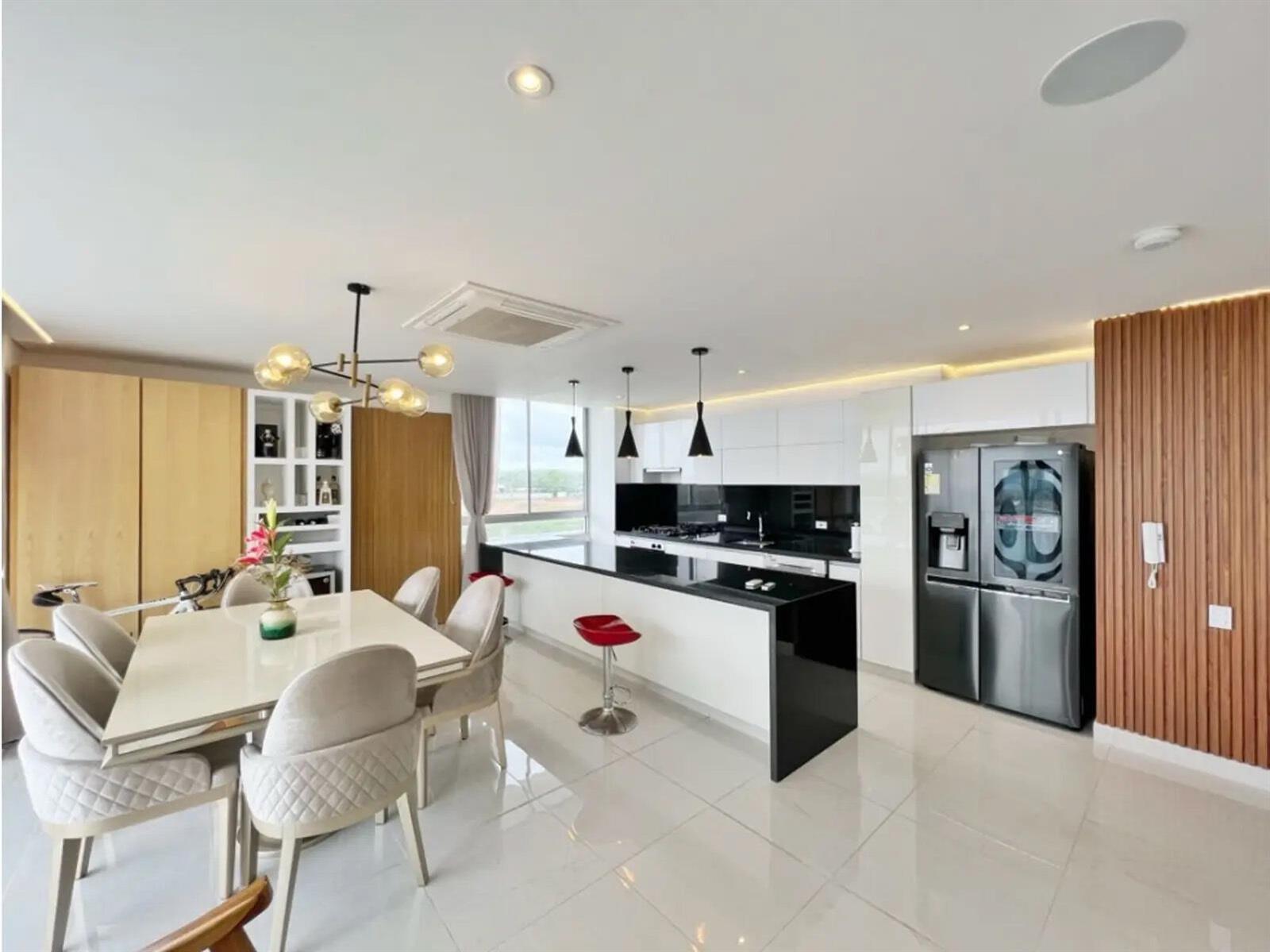 A modern open-plan kitchen and dining area featuring white cabinetry, black countertops, and tile flooring — Km 8 Via Al Mar, FL