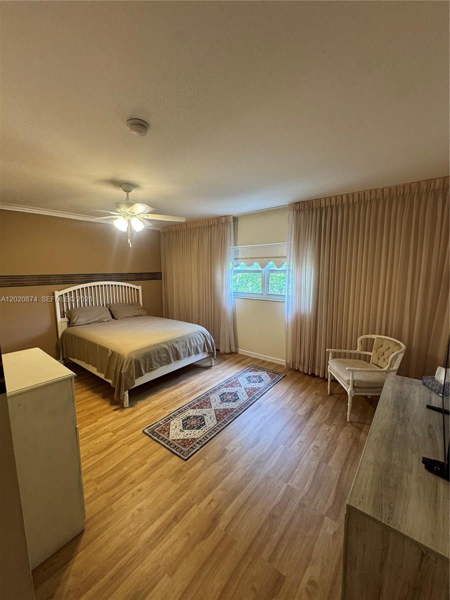 A bedroom features a bed, a patterned rug, a chair, and floor-to-ceiling curtains — 6731 Cypress Rd # 410, Plantation FL 33317, PLANTATION, FL