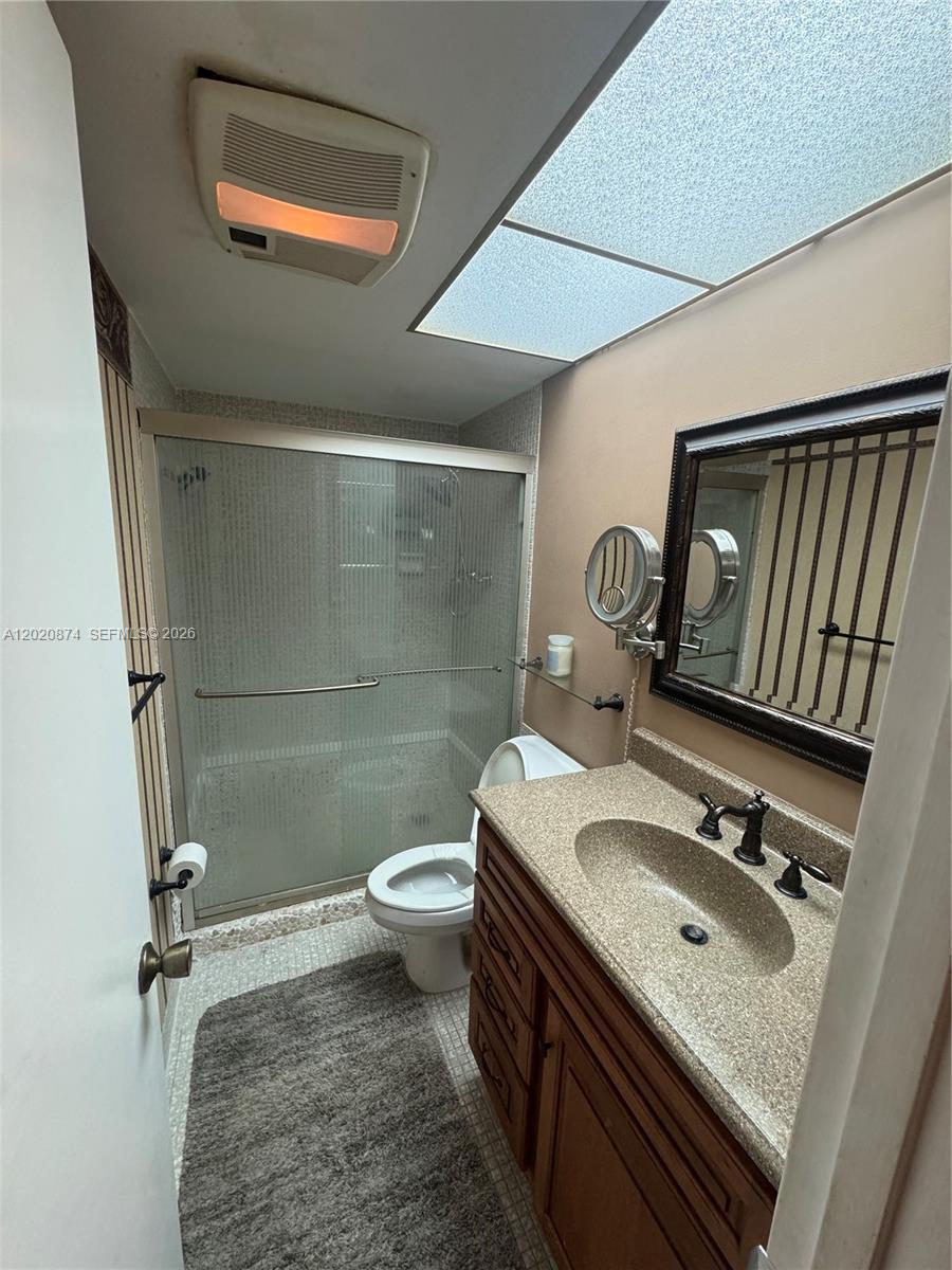 A bathroom features a vanity with a speckled countertop, a toilet, and a glass-enclosed shower — 6731 Cypress Rd # 410, Plantation FL 33317, PLANTATION, FL