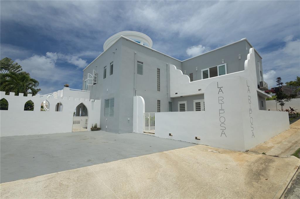 A gray multi-story building with a white wall featuring the name La Rhposa — 411 BRAVOS DE BOSTON, VIEQUES, PR