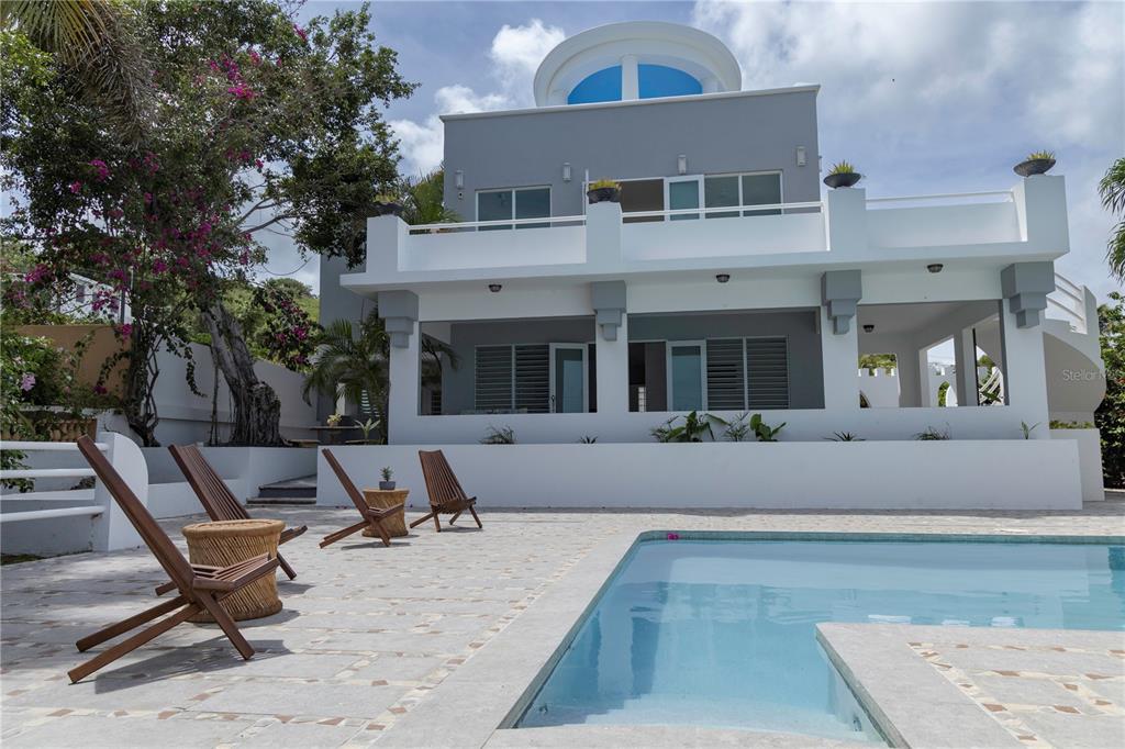A modern multi-story house with a swimming pool and patio area featuring wooden lounge chairs — 411 BRAVOS DE BOSTON, VIEQUES, PR