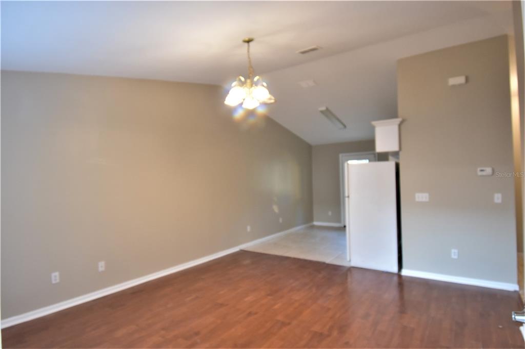 A living room with wood-look flooring, a vaulted ceiling, and a hanging light fixture — 4406 E MANGO TERRACE, TAMPA, FL