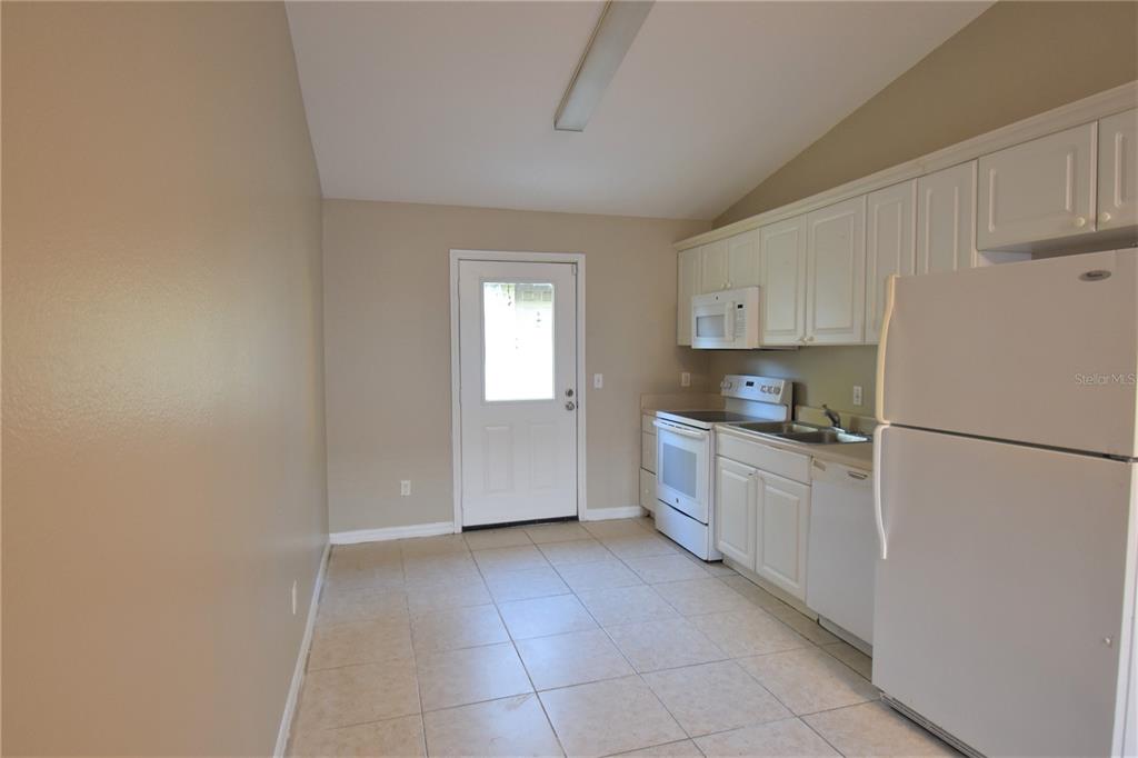A kitchen with white cabinets, white appliances, and light-colored tile flooring — 4406 E MANGO TERRACE, TAMPA, FL
