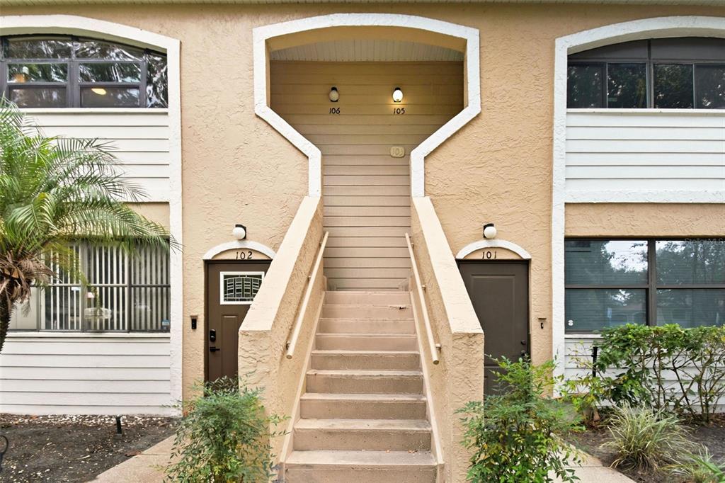 Exterior view of a two-story apartment building with stairs leading to upper-level units — 2936 S SEMORAN BOULEVARD UNIT 106, ORLANDO, FL