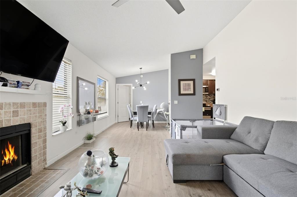A living room with a fireplace, gray sectional sofa, and an adjacent dining area — 2936 S SEMORAN BOULEVARD UNIT 106, ORLANDO, FL