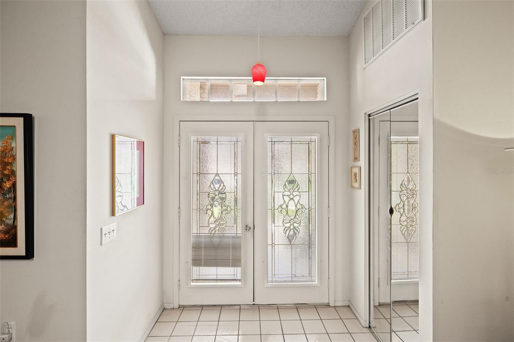 An entryway features a double door with glass inserts, tile flooring, and a red pendant light — 7392 MEADOW BROOK LANE, SPRING HILL, FL