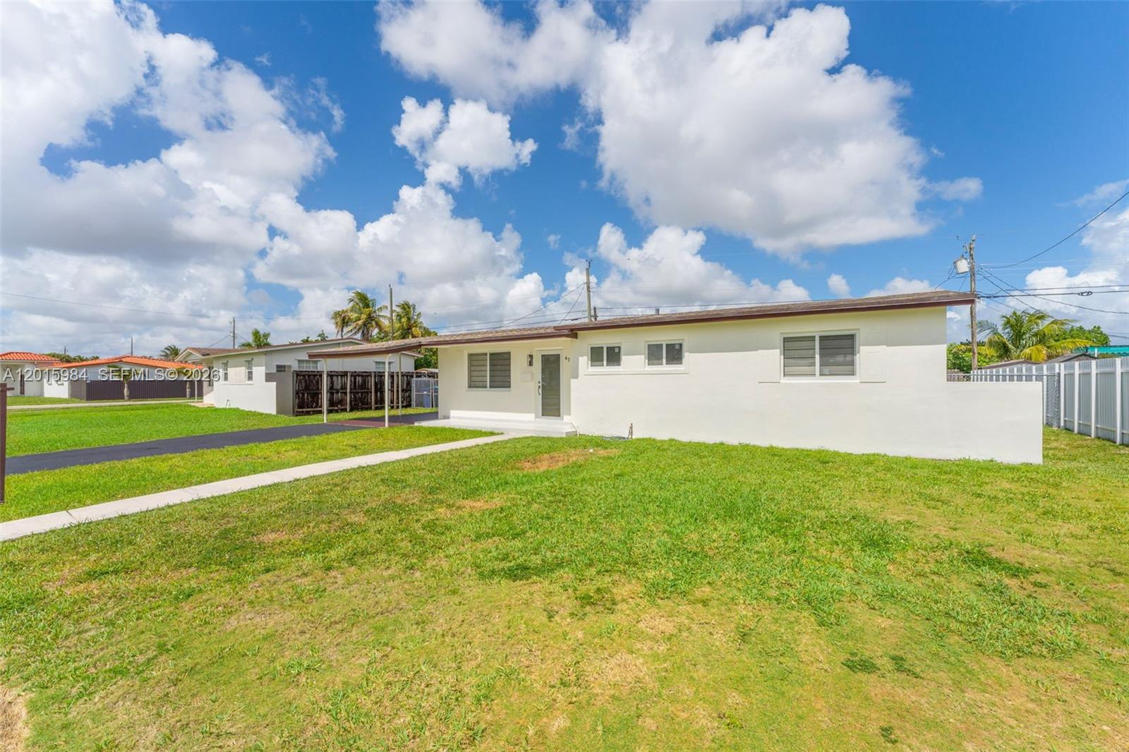 A single-story white house with a carport and a front lawn under a cloudy sky — 4211 SW 97th Pl, Miami FL 33165, MIAMI, FL