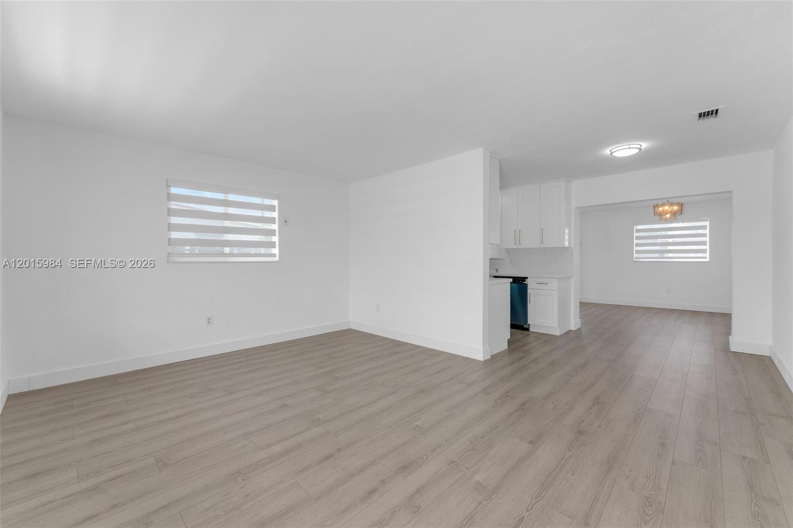 An interior view shows a living area with light wood floors and a white kitchen — 4211 SW 97th Pl, Miami FL 33165, MIAMI, FL