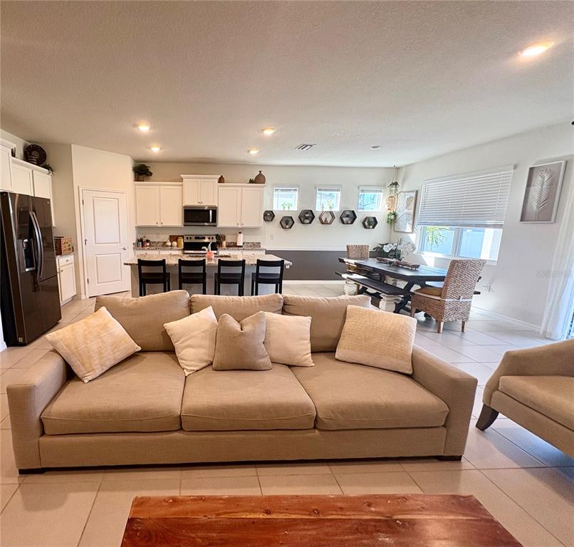 A spacious open-concept living room and kitchen featuring a large sofa and dining area — 13329 WATERLEAF GARDEN CIRCLE, RIVERVIEW, FL