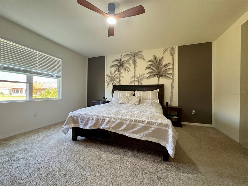 A bedroom features a bed with a palm tree mural on the wall behind it — 13329 WATERLEAF GARDEN CIRCLE, RIVERVIEW, FL