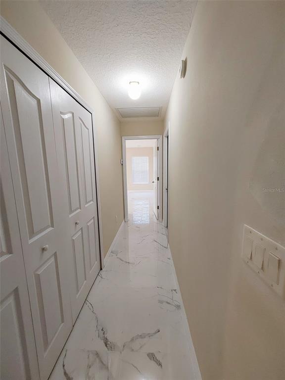 A hallway features white marble-look tile flooring, white paneled closet doors, and a light fixture — 1102 NE 21ST TERRACE, OCALA, FL