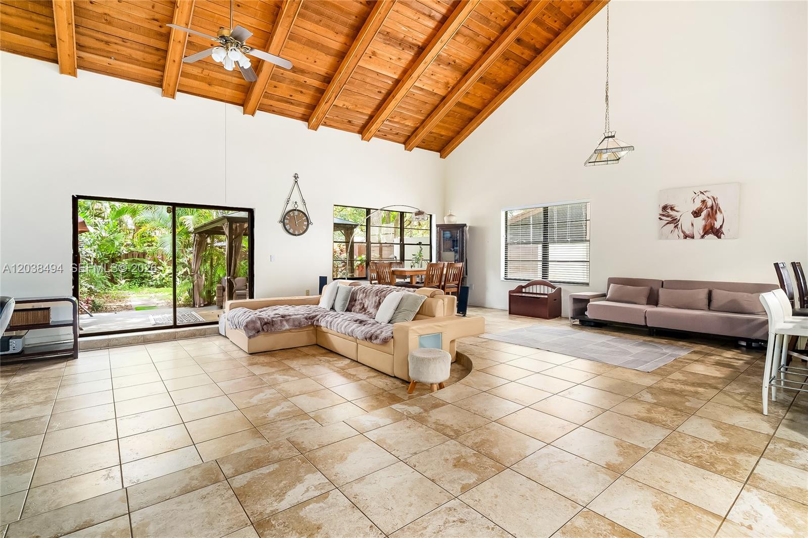A spacious living room features a vaulted wood-beam ceiling, tile flooring, and sliding glass doors — 3340 Oak Dr, Hollywood FL 33021, HOLLYWOOD, FL