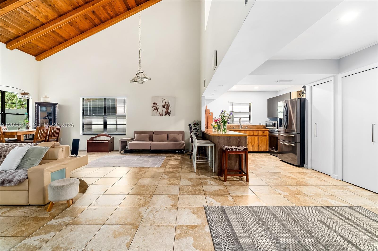 An open-concept living area features a vaulted wood-beam ceiling, tiled floors, and a kitchen — 3340 Oak Dr, Hollywood FL 33021, HOLLYWOOD, FL