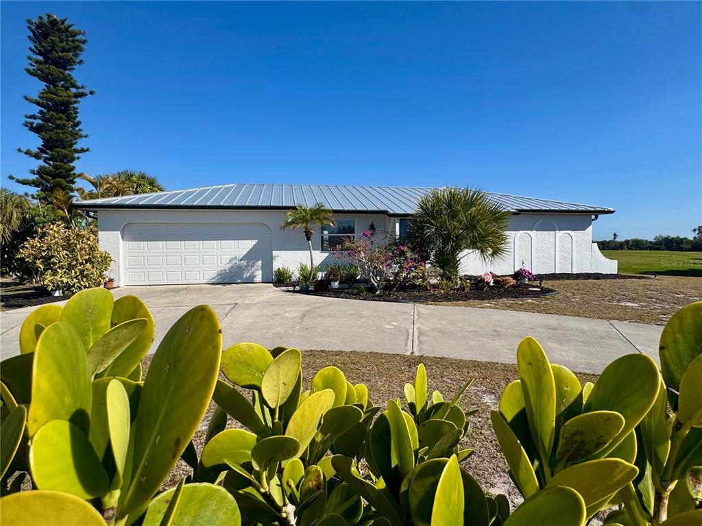A single-story white house with a metal roof and a two-car garage — 118 ROTONDA CIRCLE, ROTONDA WEST, FL